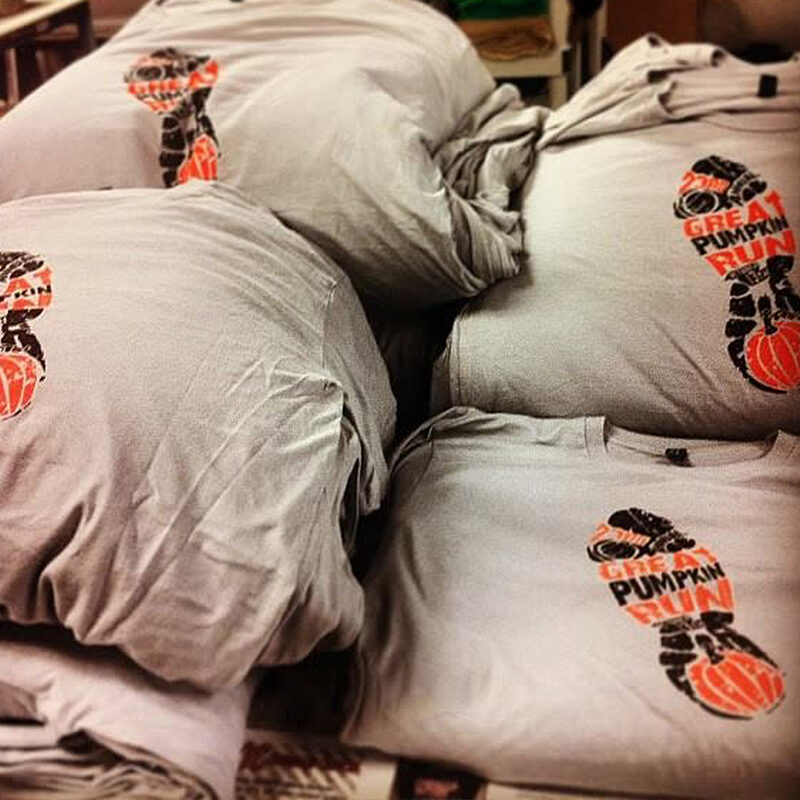 Stacks of grey race event shirts printed with an orange and black design