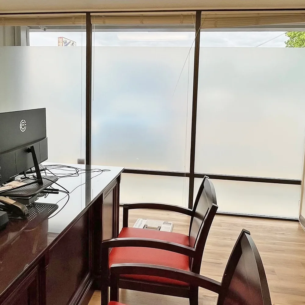 Office windows with frosted privacy film covering the lower panes, leaving clear glass above for daylight