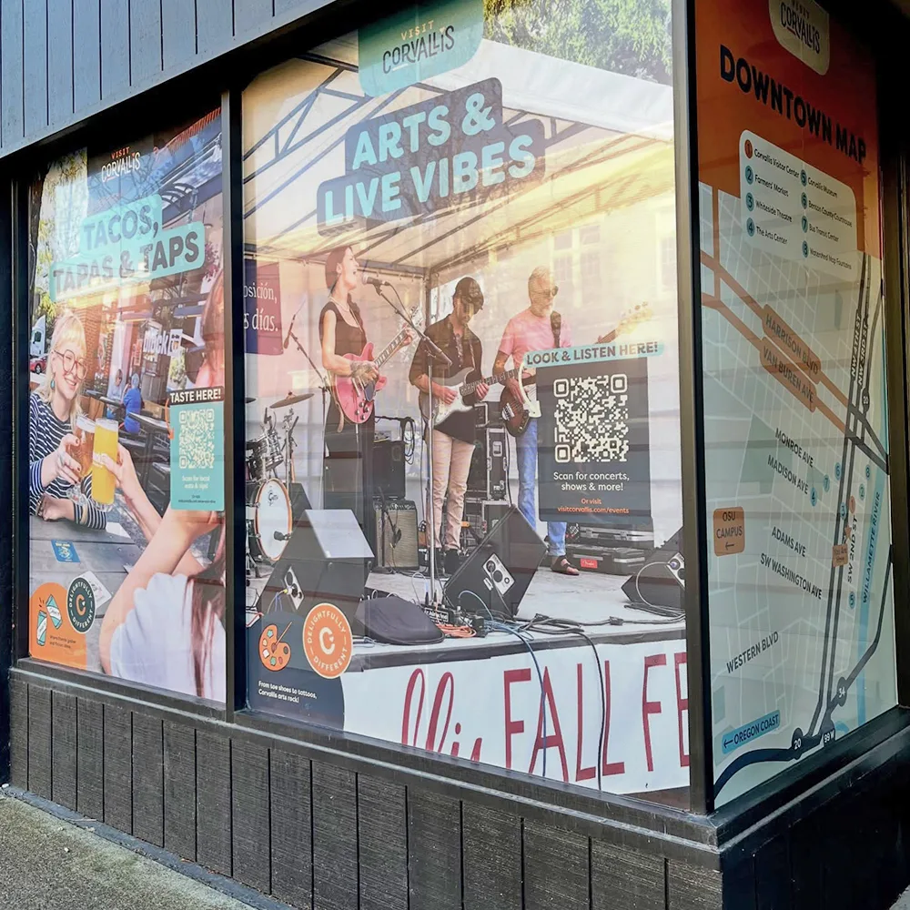 A corner storefront with full colour graphics across every window panel, including a printed map and scannable QR codes