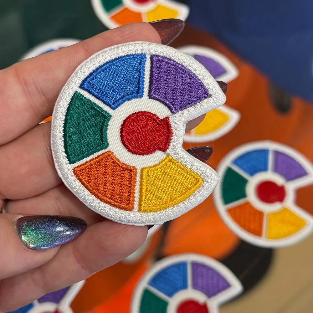 Embroidered stitched patch with a merrowed edge held in hand