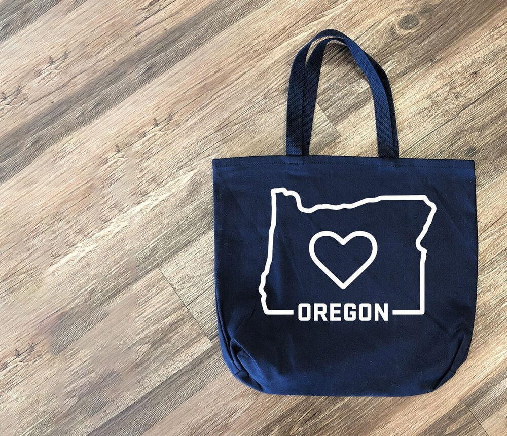 Navy canvas tote bag screen printed with an Oregon state outline and heart