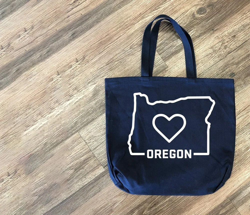 Navy canvas tote bag screen printed with an Oregon state outline and heart