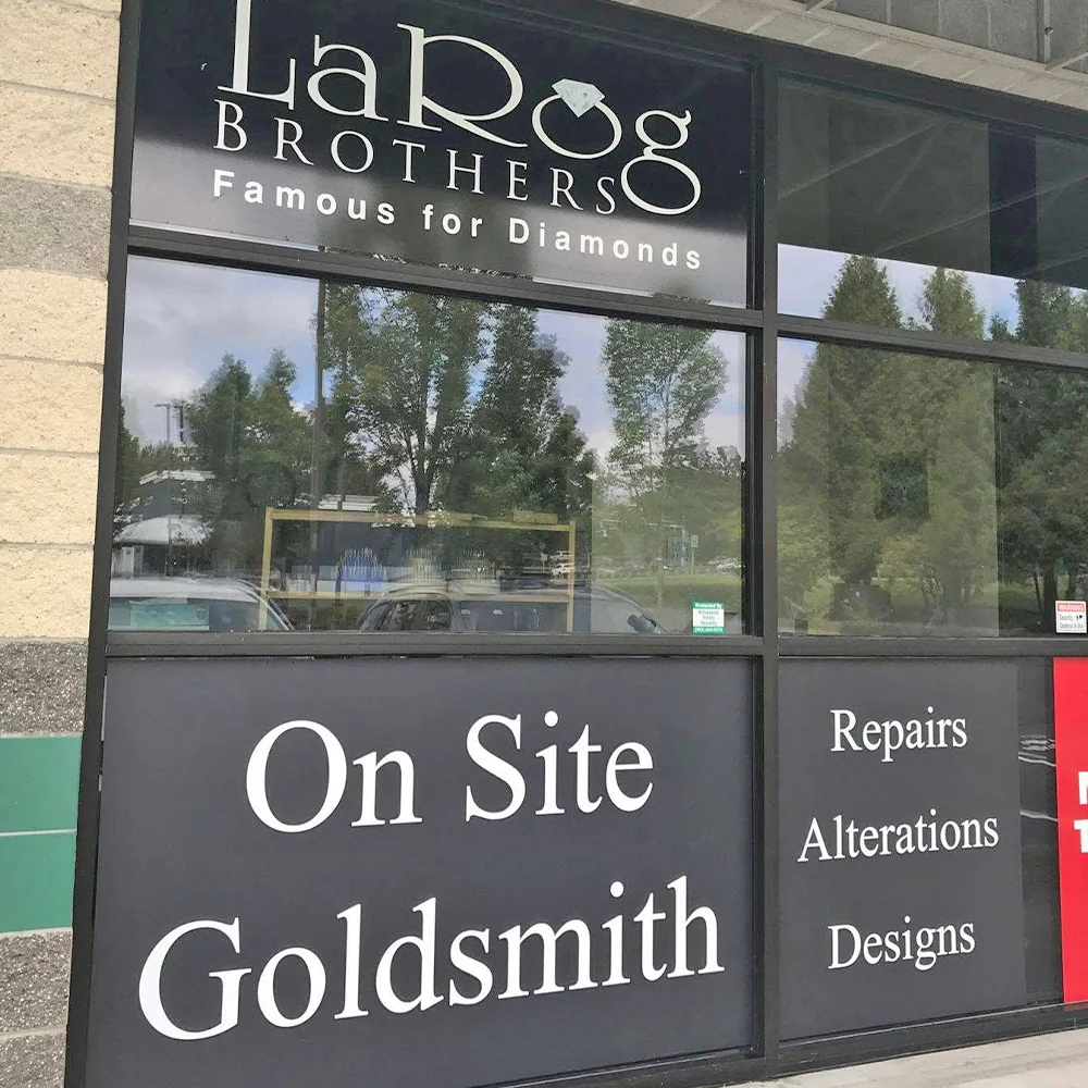 Storefront with opaque black window panels carrying white lettering for a jewellery shop, above and below clear glass